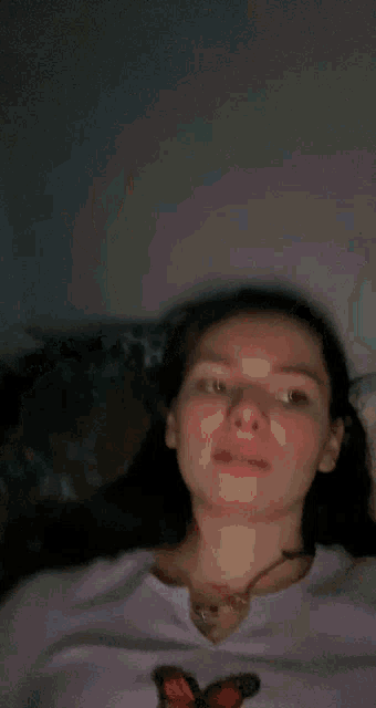 a woman wearing a purple shirt with a butterfly on it is pointing her finger at her forehead