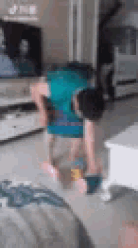 a child is doing a handstand in a living room in front of a television .