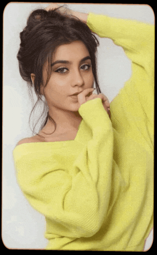 a woman in a bright yellow sweater holds her hand to her chin