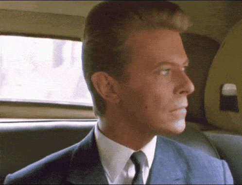 a man in a suit and tie is sitting in the back of a car