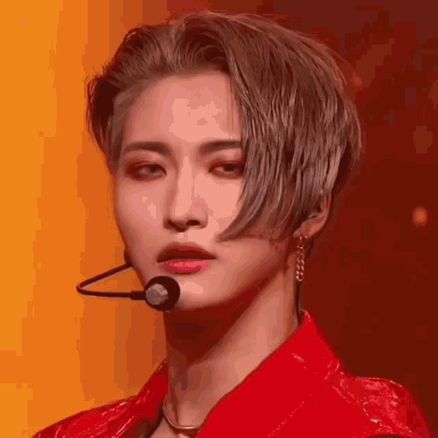 a close up of a young man wearing a red jacket and a microphone .