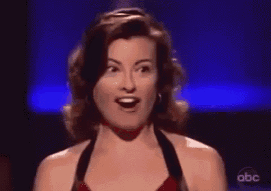 a woman in a black dress is smiling and making a funny face on a stage .