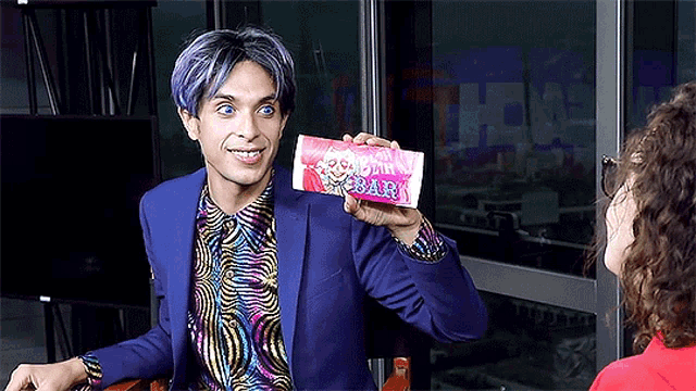a man in a blue suit is holding a candy bar that says strawberry