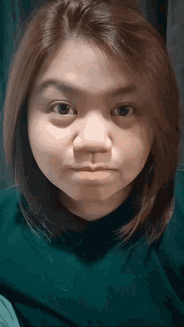 a woman wearing a green shirt is making a face