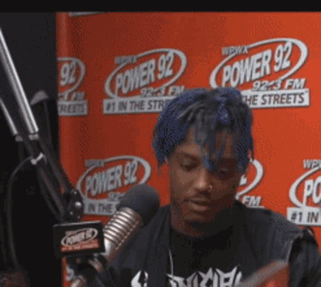 a man with blue hair stands in front of a power 92 sign
