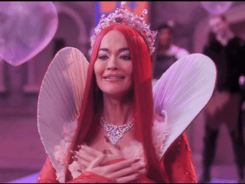 a woman with red hair is wearing a tiara and a necklace