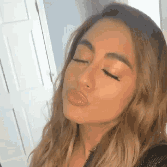 a woman is making a funny face with her eyes closed .