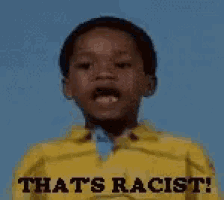 a young boy wearing a yellow shirt that says `` that 's racist '' is making a funny face .