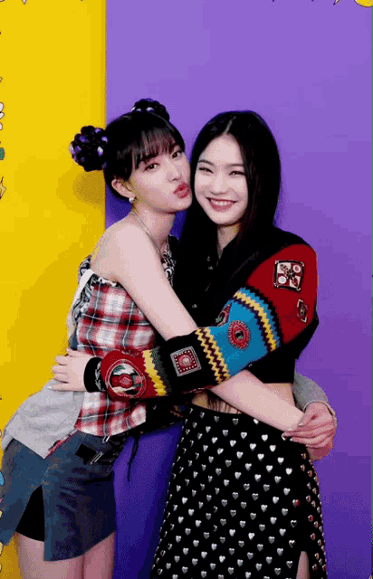 two women hugging each other with one wearing a plaid shirt with the letter o on it