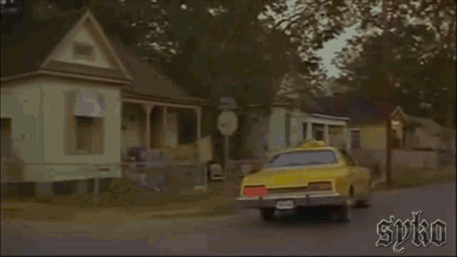 a man is getting out of a yellow car with the word spiko on the bottom right corner .
