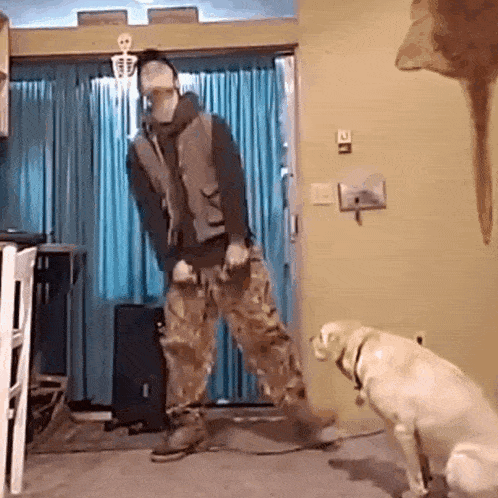 a man is dancing in a living room while a dog watches .