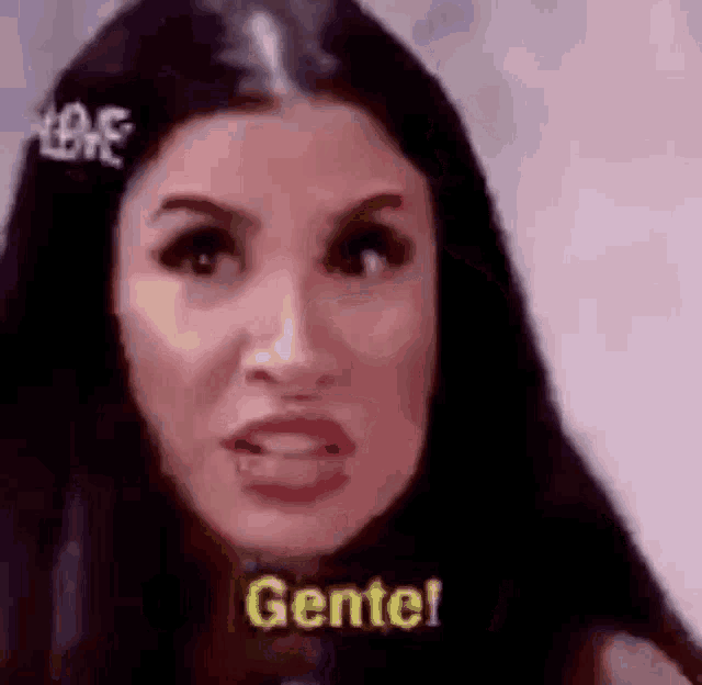 a woman with long black hair is making a funny face and saying gente !