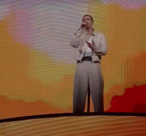 a man singing into a microphone with his arms outstretched