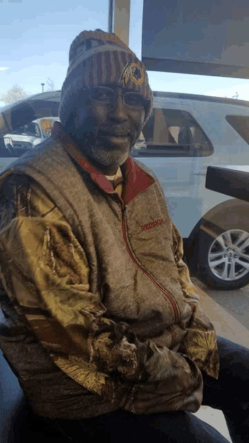 a man wearing a redskins jacket and a beanie