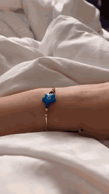 a person laying in bed with a blue bracelet on their arm