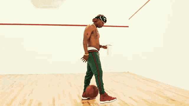 a man without a shirt is holding a basketball in a gym