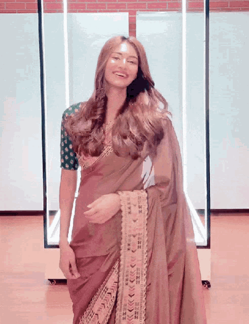 a woman in a saree with a green polka dot blouse is smiling