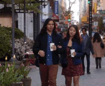 a man and a woman walking down a street with a sign that says ' abercrombie & fitch ' on it