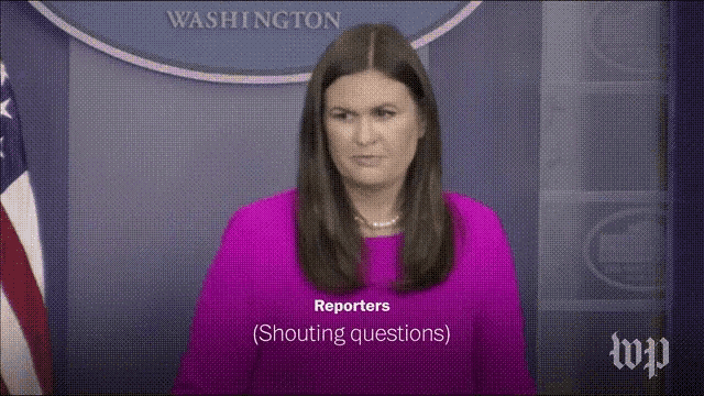 a woman in a purple shirt is talking to reporters shouting questions .