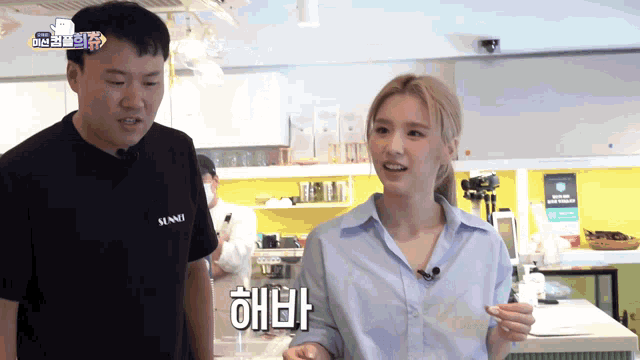 a man and a woman are standing in front of a counter and the woman is wearing a shirt that says alani on the front