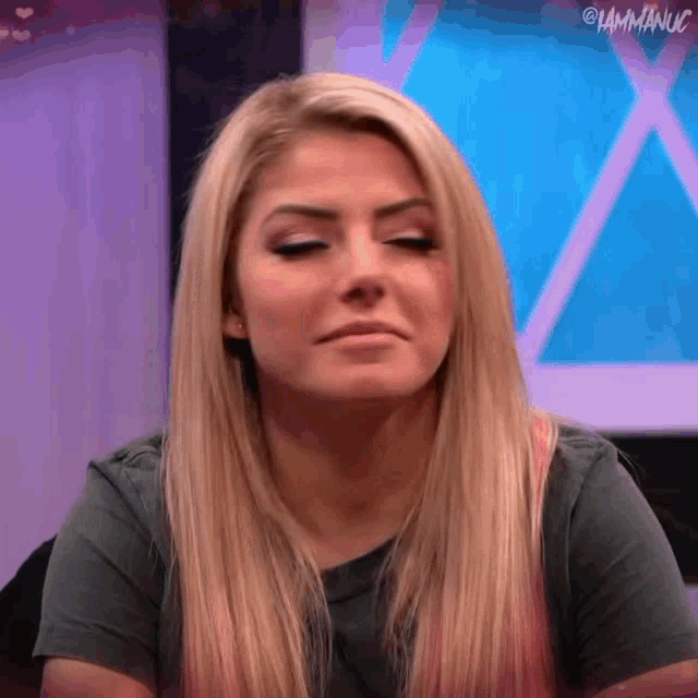 a woman with long blonde hair is making a funny face while wearing a gray shirt .