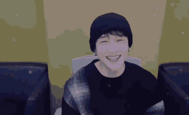 a man wearing a black hat and a black shirt is smiling