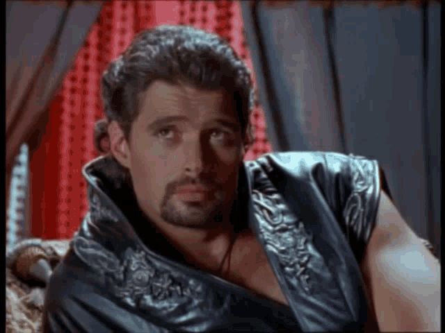 a man with a beard is wearing a black leather jacket