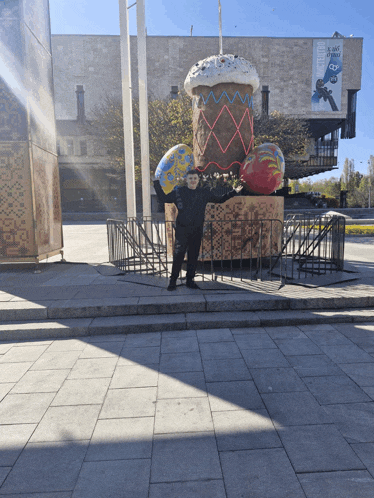 a man stands in front of a giant easter egg display