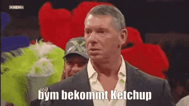 a man in a suit says bym bekommt ketchup in front of a crowd