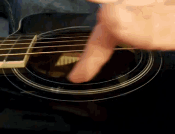 a person playing an acoustic guitar with their thumb