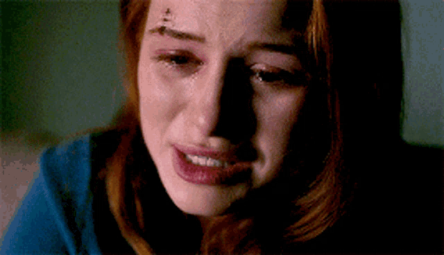 a woman with a tattoo on her forehead is crying .