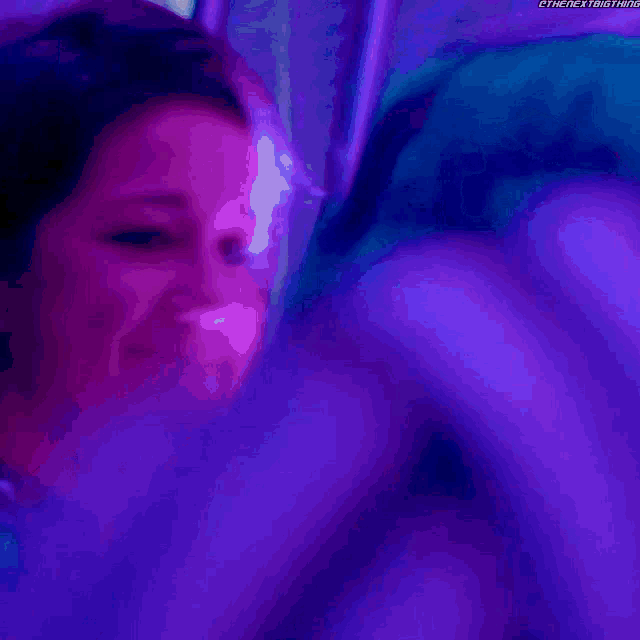 a close up of a person 's face in a dark room with a purple background