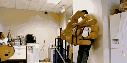 a man is carrying a giant hand on his back in an office