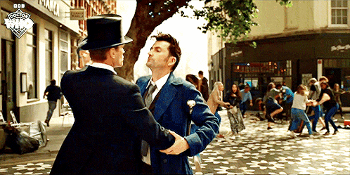 a man in a top hat talks to another man in a blue suit
