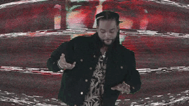 a man in a black jacket is dancing in front of a colorful screen