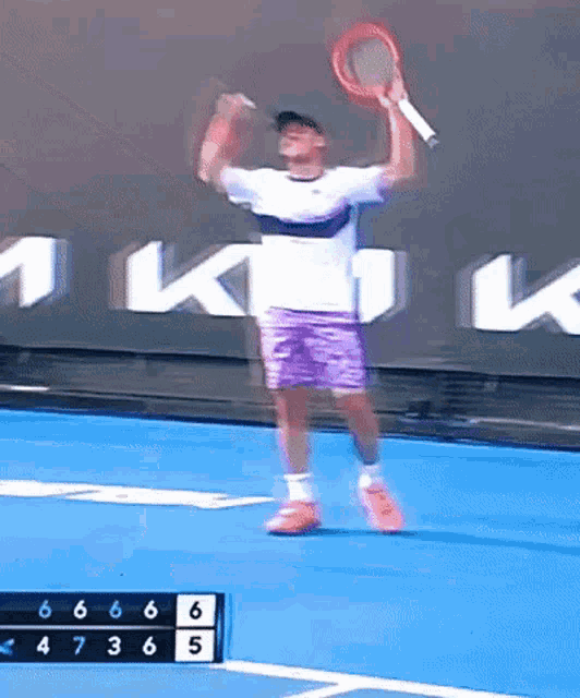 a tennis player jumps in the air while holding a racket