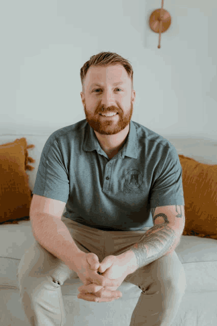 a man with a beard is sitting on a couch and smiling