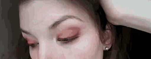 a close up of a woman 's face with red eyeshadow .