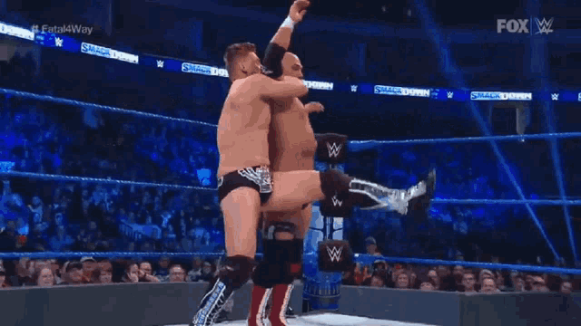 two men are wrestling in a wrestling ring on a television show .