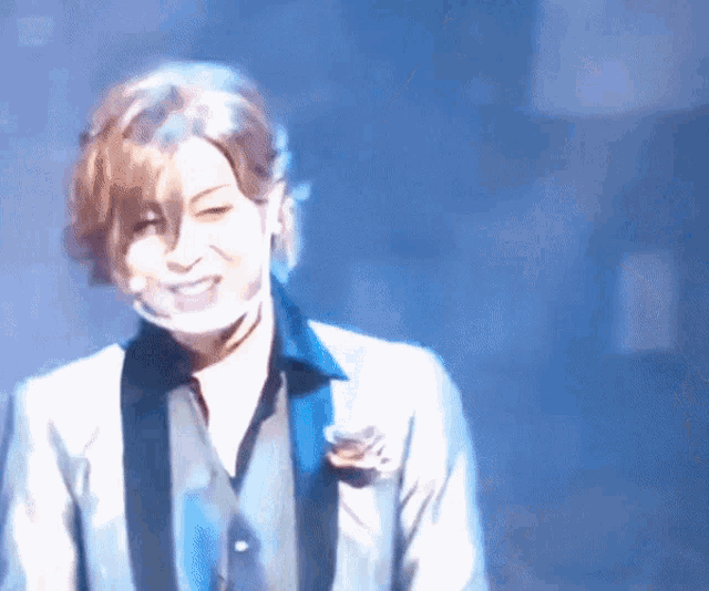 a man wearing a suit and tie is smiling on stage