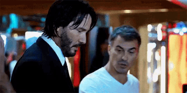 a man in a suit and a man in a white shirt are standing next to each other .