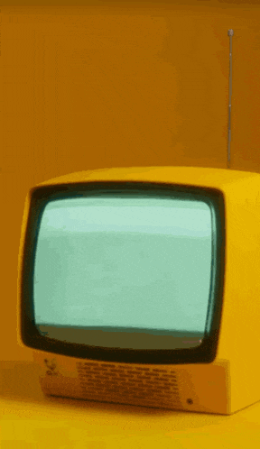 an old yellow television is sitting on a yellow table .