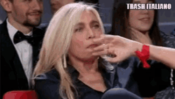 a woman is sitting in a chair with a glass of water in her hand and the words trash italiano above her .