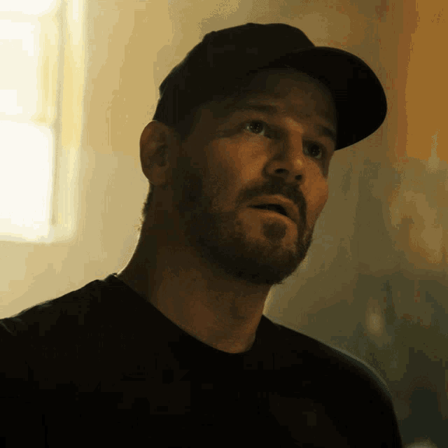 a man with a beard wears a black hat
