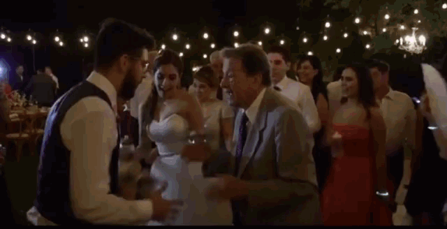a bride and groom are dancing at a wedding reception in a crowded room .