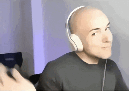 a bald man wearing headphones is smiling and looking at the camera