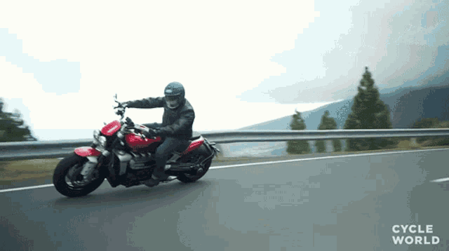 a man is riding a red motorcycle on a road with cycle world written on the bottom of the screen