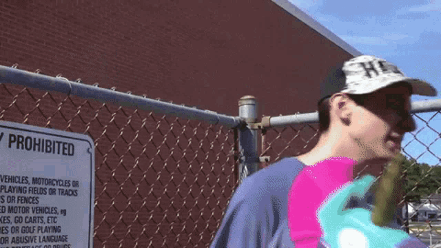 a man is standing in front of a chain link fence with a prohibited sign on it