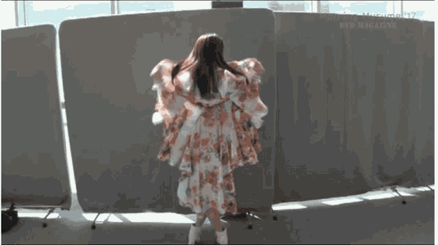 a woman in a black and white dress is dancing in front of a white wall that says fighting music new magazine