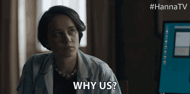 a woman is asking why us in front of a computer screen